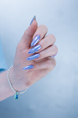Woman's hands with long nails and a light white color nail polish