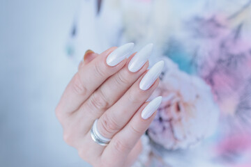 Woman's hands with long nails and a light white color nail polish