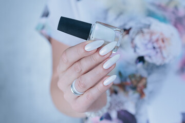 Woman's hands with long nails and a light white color nail polish