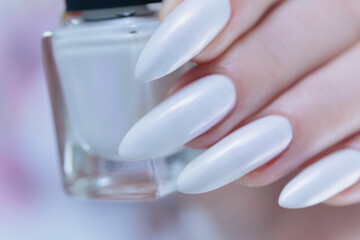 Woman's hands with long nails and a light white color nail polish