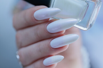 Woman's hands with long nails and a light white color nail polish