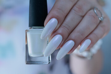 Woman's hands with long nails and a light white color nail polish