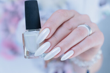 Woman's hands with long nails and a light white color nail polish