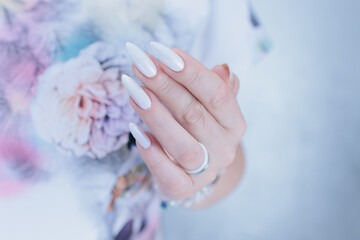 Woman's hands with long nails and a light white color nail polish
