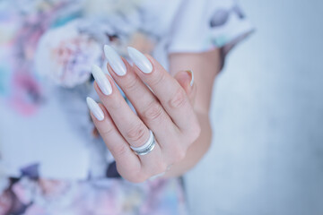 Woman's hands with long nails and a light white color nail polish