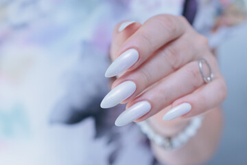 Woman's hands with long nails and a light white color nail polish