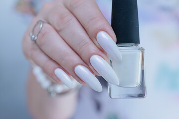 Woman's hands with long nails and a light white color nail polish