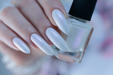 Woman's hands with long nails and a light white color nail polish