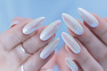 Woman's hands with long nails and a light white color nail polish