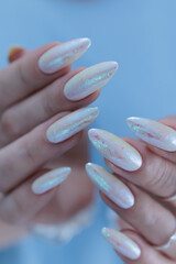 Woman's hands with long nails and a light white color nail polish