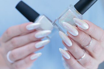 Woman's hands with long nails and a light white color nail polish