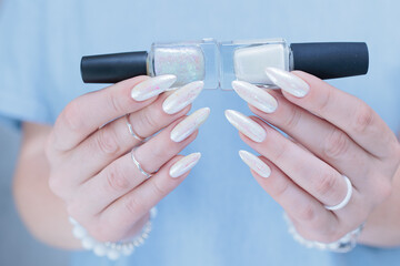 Woman's hands with long nails and a light white color nail polish