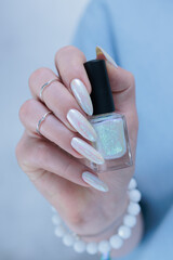Woman's hands with long nails and a light white color nail polish