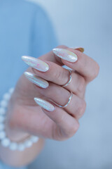 Woman's hands with long nails and a light white color nail polish