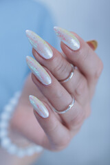 Woman's hands with long nails and a light white color nail polish
