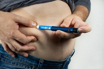 Senior man giving himself insulin injection at home, closeup. Insulin Injection Diabetes Drug Being Used For Weight Loss. Medical equipment for diabetes patient. Diabetes concept