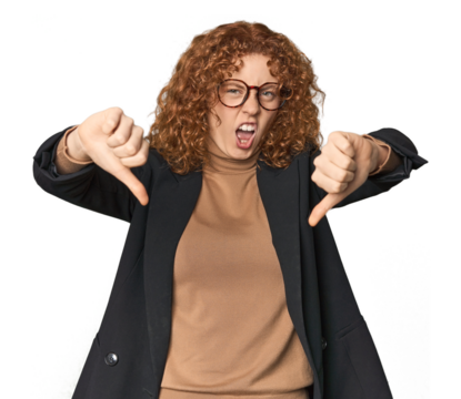 Young Caucasian redhead in business attire showing thumb down and expressing dislike.