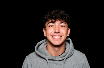 Portrait of a smiling Caucasian man in his 20s wearing a sweatshirt against a dark background.