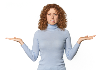 Young Caucasian redhead woman confused and doubtful shrugging shoulders to hold a copy space.