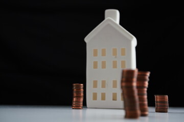 General view with left air of the image of stacked coins of different currencies in front of a house as a concept of saving for home purchase