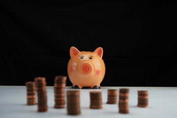 Stacked coins of different currencies in front of a piggy bank focused on the background as a concept of saving for home purchase