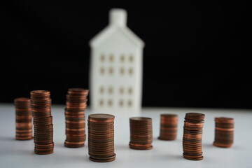 piles of coins in front of a house as a concept of saving for the purchase of a home
