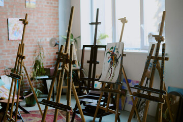 No people shot of set of wooden easels in modern art school room interior, copy space