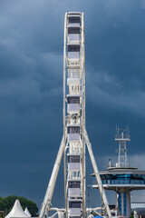 A white Ferris wheel on the beach in Travemünde under a threatening dark sky
