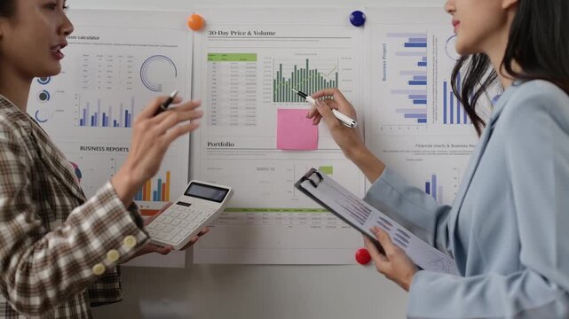 Businesswomen analyzing financial data on a whiteboard for a presentation