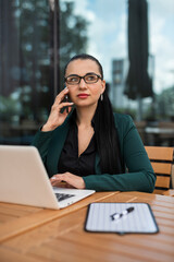 Fototapeta premium Businesswoman talking by smartphone working with tablet laptop outdoor in cafe. Business concept