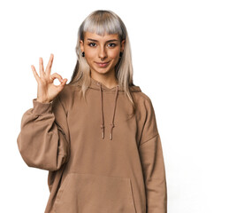 Young caucasian young woman in studio cheerful and confident showing ok gesture.