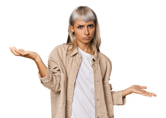 Young caucasian young woman in studio doubting and shrugging shoulders in questioning gesture.