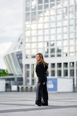 Obraz premium Young Woman in Casual Outfit Standing on Urban Rooftop With Modern Buildings in Background