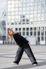 Young Woman Dancing Urban Style in Front of Modern Glass Building During Daytime