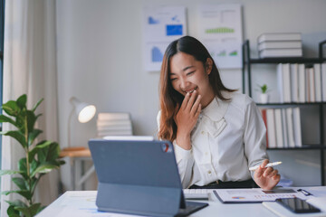 Asian businesswoman is laughing while having a video call on her tablet computer in her home office