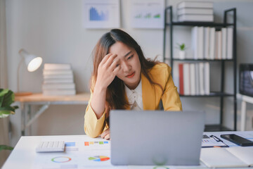 Stressed businesswoman suffering from headache while working on laptop computer and financial...