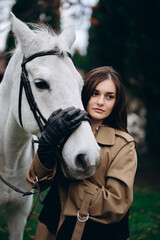Young Woman Embracing Her White Horse in a Lush Outdoor Setting During Autumn Season