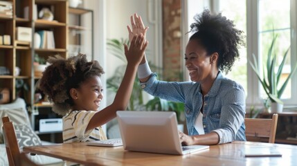 A black mother and daughter high five each other after doing homework together at home, with a laptop on the table in living room at home.