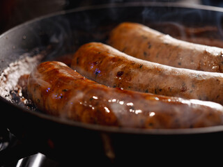 Sausages cooking in beer in a skillet at night 