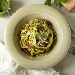 plate of tagliatelle pasta with bresaola and pesto sauce on table, top view