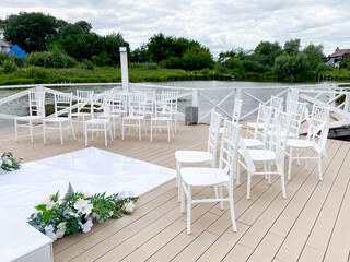 A neatly arranged row of white chairs can be seen aligned perfectly on a beautifully crafted wooden deck, showcasing a charming outdoor setting that invites relaxation and enjoyment