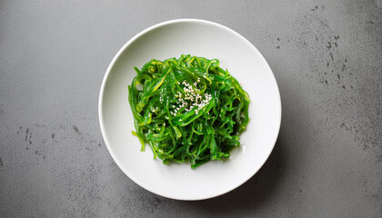 Green seaweed salad in white plate. Tasty food. Delicious and healthy dish. Close-up. Flat lay