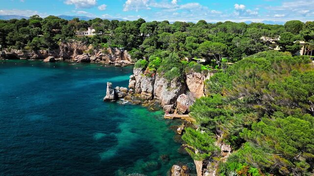 View from above of Billionaire Bay and rocky beach near coastal path on the Cap Antibes. Aerial view of the picturesque bay with luxurious villas, breathtaking views, and crystal-clear waters on Frenc