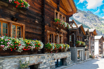 Picturesque street of chalets with flowers in window flower boxes in Zermatt, Switzerland, during...