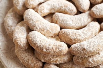 Close up of homemade Christmas cookies called Kipferl or vanilla crescents coated in sugar on a plate