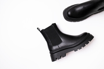 Black leather women classic boots on plain white background. Top view flat lay. Autumn spring winter fashion boots, women's shoes, footwear with thick soles. Fashion and style