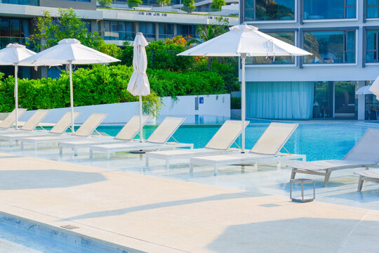 Empty swimming pool with sunbed and white umbrella in resort hotel for vacation leisure and white sand,resort neary sea and beach in summer..