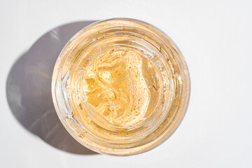 24k gold skin care cream gel in a glass jar close up. Beauty treatment product texture macro. Top view