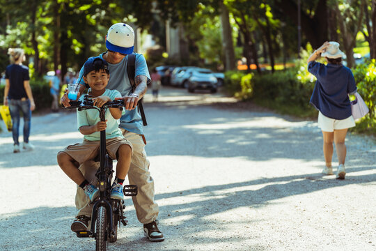 Father teaching son to ride bicycle in sunny park