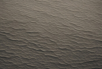 Obraz premium Aerial view of textured sand dunes, showcasing intricate patterns and waves in the sand. The color palette is muted, with shades of brown and beige, creating a serene and natural landscape.